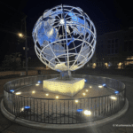 Illuminated metal globe sculpture at night