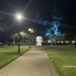 Night pathway to glowing globe sculpture